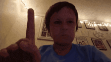 a young boy in a blue shirt is pointing up with his finger