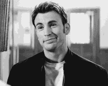 a black and white photo of a man wearing a jacket and smiling .