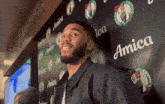 a man stands in front of a wall with celtics logos