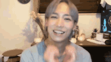 a young man with gray hair is making a heart shape with his hands .