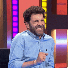 a man with a beard wearing a blue shirt with a ralph lauren logo on the collar