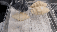 two croissants are sitting on a wire rack on a paper towel .