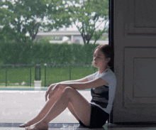 a woman sits on the floor looking out of a window