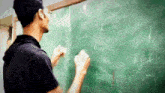 a man writes on a green chalkboard with the word newton visible