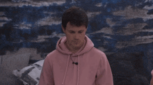 a young man wearing a pink hoodie with a microphone on his neck