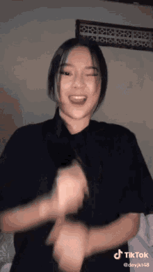a woman in a black t-shirt is dancing in a room .