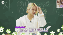 a girl with blonde hair is sitting at a desk in a classroom with other girls .