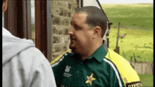 a man wearing a green shirt with a yellow star on the front is talking to another man