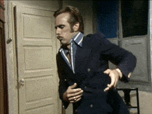 a man in a suit and tie is standing in front of an open door