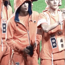 a group of young men wearing orange sweatshirts with the letter p on the side