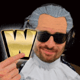 a man wearing a wig and sunglasses is pointing at a gold letter w