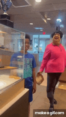 a woman in a pink shirt laughs while walking with a boy