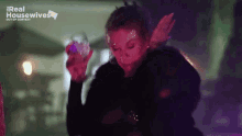 a woman with glitter on her face is holding a glass in front of a sign that says real housewives out of context