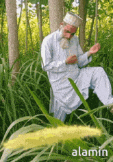 a man with a beard and a hat is kneeling in the grass