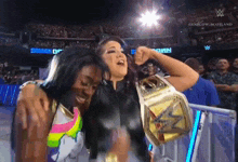two women are standing next to each other in a wrestling ring holding a wrestling championship belt .