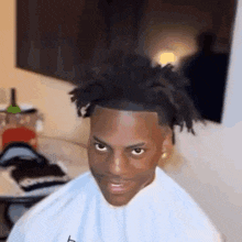 a man with dreadlocks is sitting in a chair in a room .