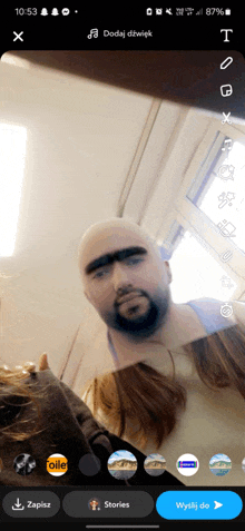 a phone screen shows a man with a beard and mustache