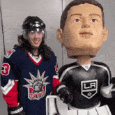 a man in a nyr jersey stands next to a statue of himself