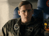 a man in a pilot 's uniform and glasses is sitting in a plane .