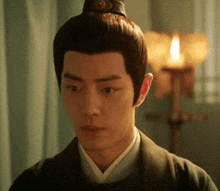a close up of a man 's face with a candle behind him