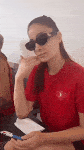a woman wearing sunglasses and a red t-shirt with a bird on it