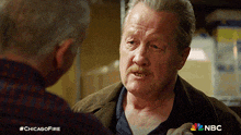 a man with a mustache is talking to another man with #chicagofire written below him