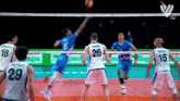 a volleyball player with the number 26 on his back jumps to block a ball