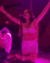 a woman in a pink dress is dancing on a stage with a microphone in her hand .