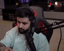 a man with a beard is sitting in front of a microphone .