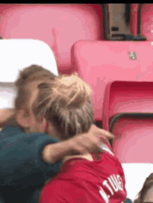 two women hugging in a stadium with one wearing a red shirt that says ' a. tucker ' on it