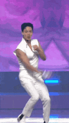 a man is dancing on a stage in front of a purple background .