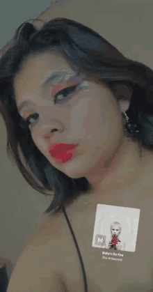 a woman wearing red lipstick is listening to a song called baby 's on fire