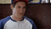 a young man wearing a baseball cap and a blue and white sweater