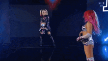 a woman with pink hair is standing next to another woman holding a microphone .