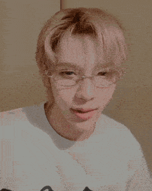 a young man wearing glasses and a white shirt is waving his hands