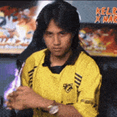 a man wearing a yellow shirt with the word kelr on the bottom right