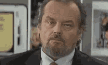 a man with a beard wearing a suit and tie is looking at the camera .