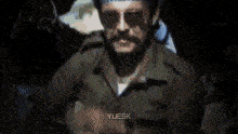 a man with a beard and sunglasses is wearing a head scarf .