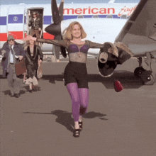 a woman dancing in front of an american eagle airplane
