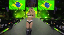 a woman in a bikini is walking down a runway in front of a green and yellow flag .
