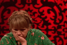 a woman in a green shirt is sitting in front of a red background with the words what you 're saying