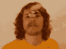 a man with long hair and a mustache is wearing an orange shirt with the word nike on it