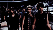 a group of men are standing next to each other and one has a tattoo on his arm