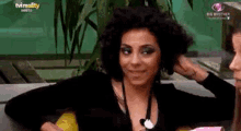 a woman with curly hair is sitting on a couch with her hand on her head .