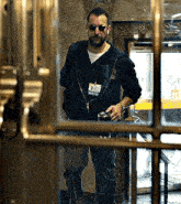 a man with a beard is standing in front of a door holding a can of soda .
