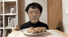 a man is sitting at a table with a plate of food on it .