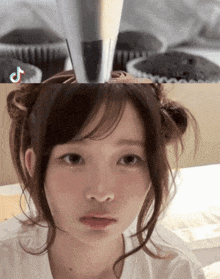 a girl with a cupcake on her head with a tiktok logo in the background