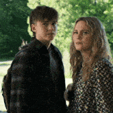 a woman and a boy are standing next to each other and looking at the camera