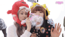 two girls wearing hats blowing soap bubbles with the words everglow subs in the background