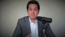 a man in a suit stands in front of a microphone that says shure on it
